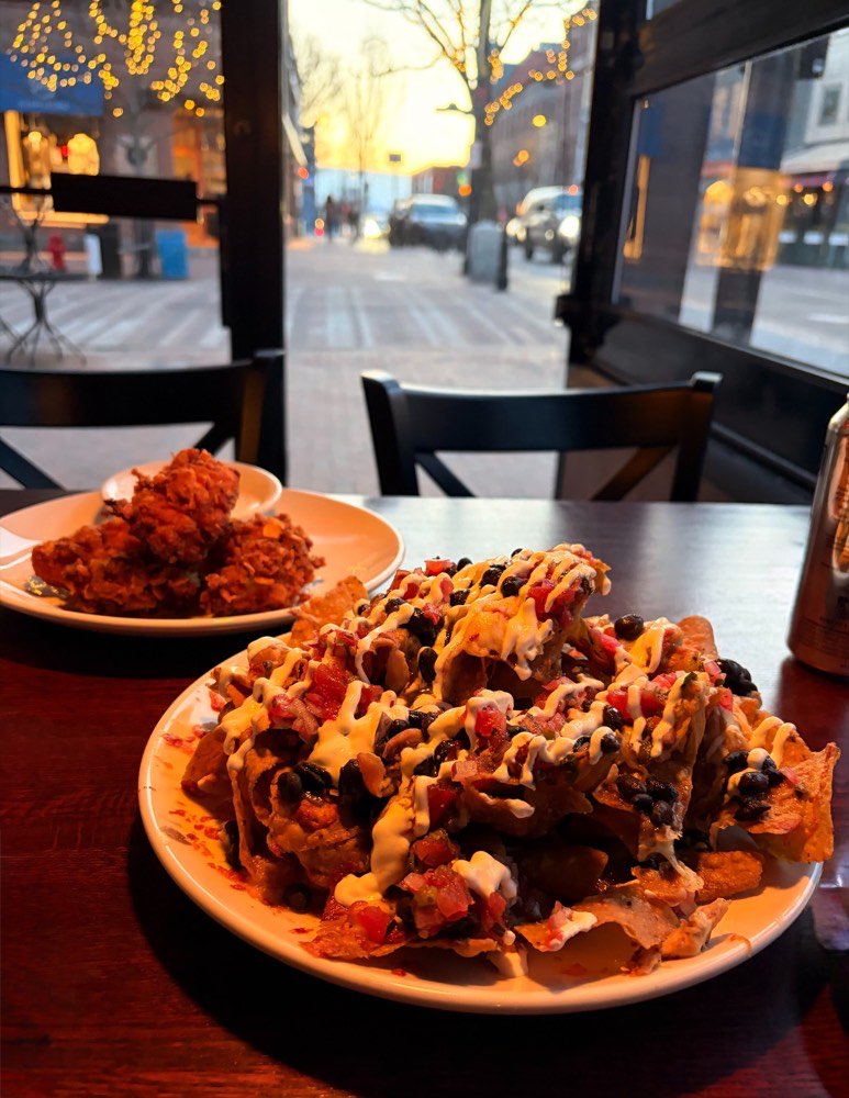 Nachos and fried chicken on a window table, Church Street at sunset outside